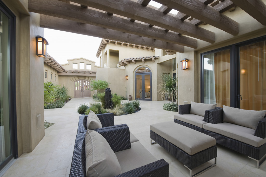 Covered outdoor living area with couches and a table.